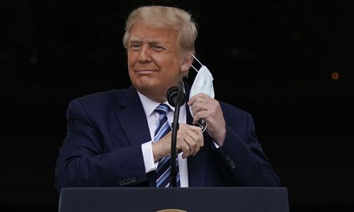 도널드 트럼프 미국 대통령이 10일(현지시간) 백악관 블루룸 발코니에서 지지자들을 상대로 연설하기 위해 마스크를 벗고 있다. 워싱턴=AP연합뉴스