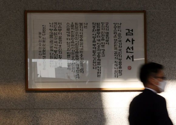 윤석열 검찰총장의 직무 집행정지 처분에 반대하는 검찰의 집단행동이 이어지고 있는 가운데 27일 오전 서울 서초구 서울중앙지검 청사에 걸린 검사선서 앞으로 관계자가 지나가고 있다. 연합뉴스