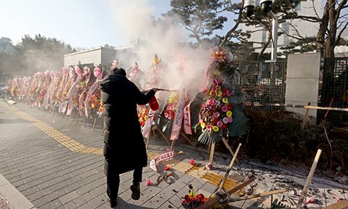5일 오전 서울 서초구 대검찰청 앞에서 한 남성이 윤석열 검찰총장 응원화환에 불을 붙이자 대검 보안요원들이 달려와 불을 끄고 있다. 연합뉴스