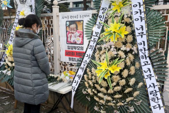 학대를 받아 숨진 것으로 알려진 정인이 양부모에 대한 재판을 하루 앞둔 12일 오전 서울 양천구 서울남부지방검찰청 앞에 마련된 정인이 영정 앞에서 한 시민이 헌화하고 있다. 뉴시스
