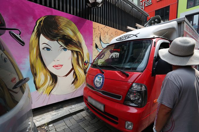 29일 윤석열 전 검찰총장의 아내 김건희씨를 비방하는 벽화가 그려진 서울 종로구 한 서점 외벽앞을 보수 단체 관계자들이 차량으로 가리고 있다. 뉴스1