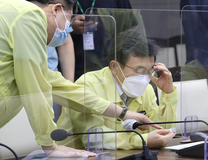 권덕철 보건복지부 장관(사진 오른쪽)이 지난 28일 오전 정부세종청사에서 김부겸 국무총리 주재로 열린 신종 코로나바이러스 감염증(코로나19) 대응 중앙재난안전대책본부 회의에 참석해 이기일 중앙재난안전대책본부 제1통제관이 가지고 온 모더나 백신병을 살피며 대화하고 있다. 세종=연합뉴스