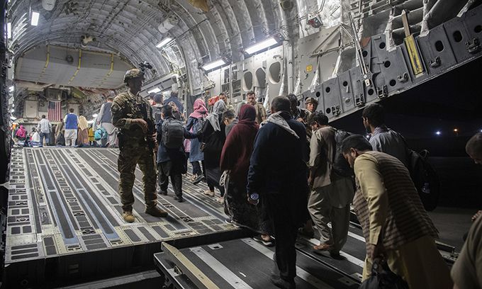 이슬람 무장조직 탈레반이 장악한 아프가니스탄 수도 카불의 하미드 카르자이 국제공항에서 22일(현지시간) 미군이 경비를 서는 가운데 국외로 탈출하려는 아프간 난민들이 미 공군 C-17 수송기에 오르고 있다. 미국과 동맹국은 철군 시한인 이달 31일을 앞두고 아프간 대피 작전을 서두르고 있다. 카불=AP연합뉴스