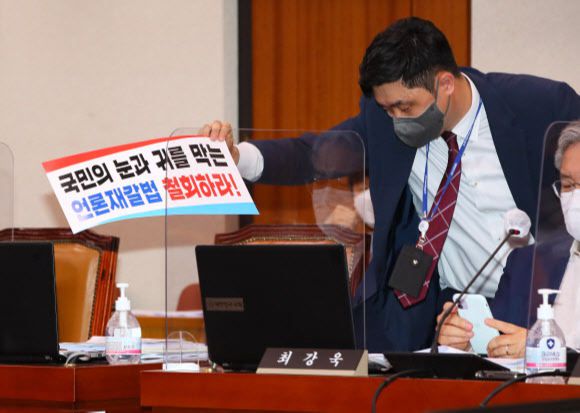 25일 서울 여의도 국회에서 열린 법제사법위원회 전체회의에서 법사위 관계자가 국민의힘 의원들이 퇴장한 뒤 남겨져 있던 언론중재법 반대 손팻말을 정리하고 있다. 뉴스1