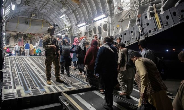 이슬람 무장조직 탈레반이 장악한 아프가니스탄 수도 카불의 하미드 카르자이 국제공항에서 22일(현지시간) 미군이 경비를 서는 가운데 국외로 탈출하려는 아프간 난민들이 미 공군 C-17 수송기에 오르고 있다. 미국과 동맹국은 철군 시한인 이달 31일을 앞두고 아프간 대피 작전을 서두르고 있다. 카불=AP연합뉴스