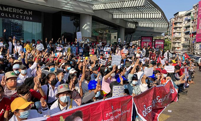 지난 2월 10일 미얀마 양곤의 한 교차로에서 아웅산 수치 현수막을 든 군사정부 반대 시위대가 저항의 상징인 세 손가락 경례를 하고 있다. 양곤=AP뉴시스