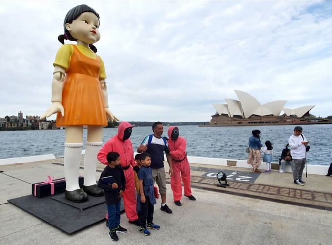 호주 시드니의 명소인 오페라하우스가 보이는 해변에 자리잡은 ‘오징어 게임’ 속 캐릭터 영희 인형 앞에 관광객이 모여 기념촬영을 하고 있다. 세계일보 자료사진