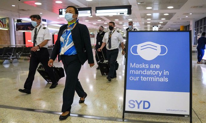 28일(현지시간) 호주 시드니 공항 터미널에 '마스크 착용 의무' 안내판이 설치돼 있는 가운데 여객기 승무원들이 이동하고 있다. 시드니 AP=연합뉴스