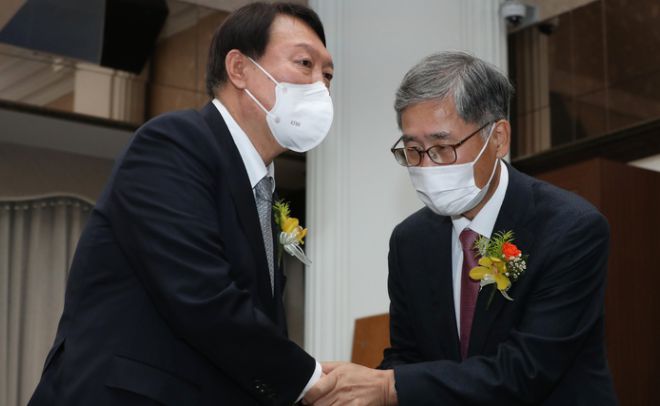 윤 후보가 지난해 11월9일 서울 중구 프레스센터에서 열린 신평(사진 오른쪽) 변호사 출판기념회에서 신 변호사와 악수하고 있는 모습. 뉴시스