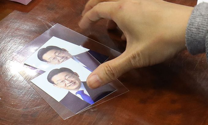 제20대 대통령 후보자 등록 첫날인 13일 경기 과천시 중앙선거관리위원회에서 관계자가 더불어민주당 이재명 대선 후보의 사진을 살펴보고 있다. 국회사진기자단