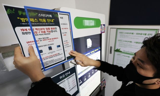 지난 1월4일 서울 서대문구 신촌 한 스터디카페에서 관계자가 방역패스 안내문을 제거하고 있다. 연합뉴스