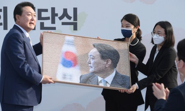 윤석열 대통령 당선인(왼쪽)이 6일 오후 서울 종로구 삼청동 대통령직 인수위원회에서 열린 인수위 해단식에 참석해 인수위 관계자 450여명 사진으로 꾸며진 기념품을 전달받고 있다. 뉴시스