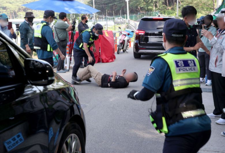 16일 경남 양산 평산마을 문재인 전 대통령의 사저 앞에서 보수단체 시위자가 도로에 누워 문 전 대통령을 예방하고 돌아가는 한덕수 국무총리 탑승 차량 행렬을 가로막고 있다. 양산=뉴스1