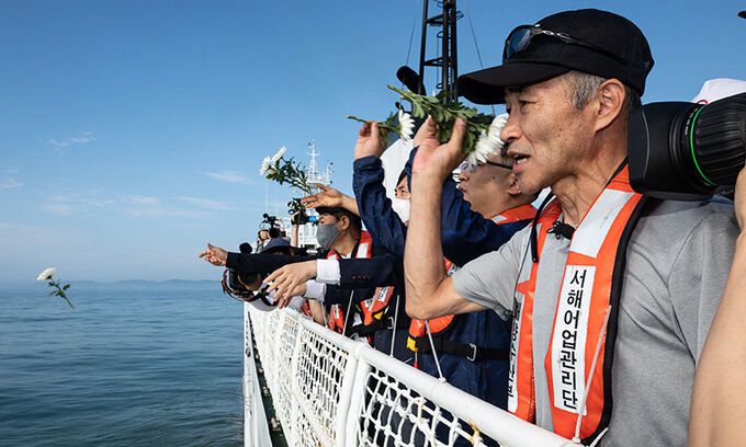서해에서 북한군에 의해 피살된 해양수산부 공무원의 형 이래진 씨(오른쪽)를 바롯한 참석자들이 지난 2일 국가어업지도선 무궁화 35호에 올라 연평도 인근 사고 현장 주변 해역을 지나며 선상에서 열린 위령제에서 바다를 향해 헌화하고 있다. 뉴스1