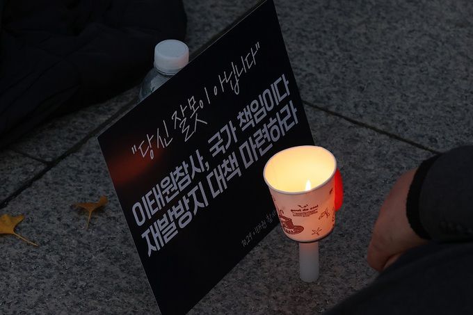 지난 19일 오후 서울 용산구 서울 지하철 6호선 녹사평역 인근에서 열린 참여연대 주관 ‘10.29 이태원 참사 시민 추모 촛불 : 당신 잘못이 아닙니다’에 참여한 시민 앞에 촛불 등이 놓여 있다. 연합뉴스