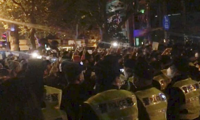 지난 26일 중국 상하이에서 경찰들이 고강도 코로나19 봉쇄정책에 반대하는 시위를 벌이는 시민들을 지켜보고 있다. 상하이=AP연합뉴스