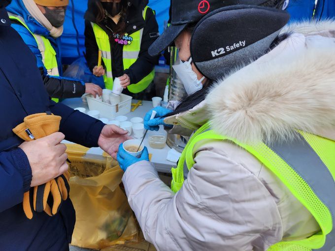이재명 대표 지지자가 이 대표 응원 집회 참여자들에게 차를 나눠주고 있다.