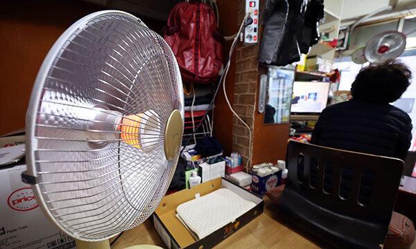 서울 중구의 한 가게에서 상인이 전기난로로 추위를 피하고 있다. 연합뉴스