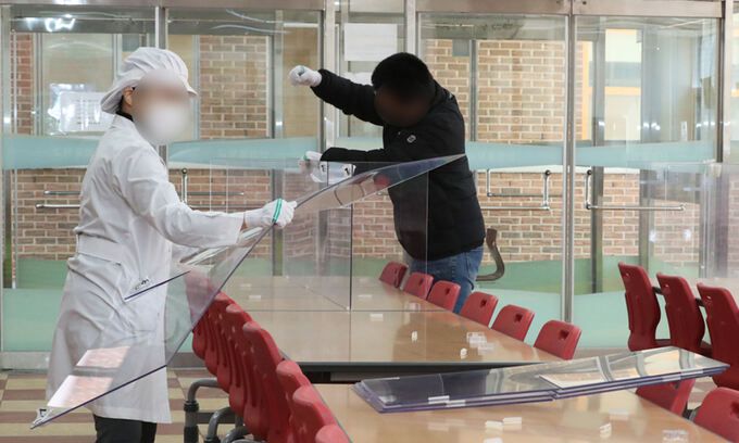 27일 광주의 한 중학교 급식실에서 투명 가림막 철거 작업이 진행 중이다. 실내마스크 해제 등 일상 회복이 이뤄지면서 교육 당국은 새 학기를 앞두고 기존보다 완화한 방역 지침을 각급 학교에 전달했다. 연합뉴스