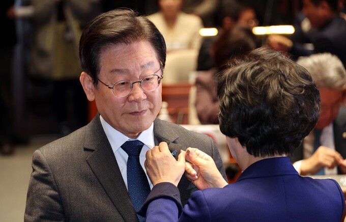 김상희 더불어민주당 대일굴욕외교대책위원장(오른쪽)이 16일 오후 서울 여의도 국회 예산결산특별위원회 회의장에서 열린 의원총회에 참석한 이재명 대표에게 태극기 배지를 달아주고 있다. 서상배 선임기자