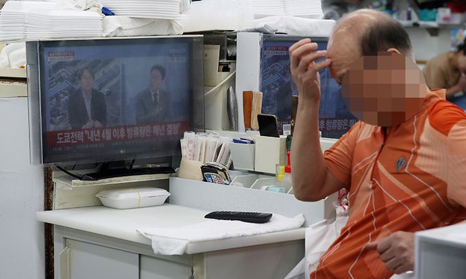 일본 정부가 후쿠시마 원전 방사능 오염수 방류를 시작한 24일 부산 수영구 민락수변공원 인근 한 회센터에서 상인들이 오염수 방류 관련 뉴스를 시청하고 있다. 뉴스1