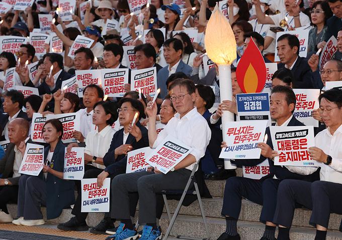 이재명 더불어민주당 대표가 7일 저녁 서울 여의도 국회 본청 앞 계단에서 열린 '민주주의 회복 촛불문화제'에서 촛불과 손 피켓을 들고 있다.뉴스1