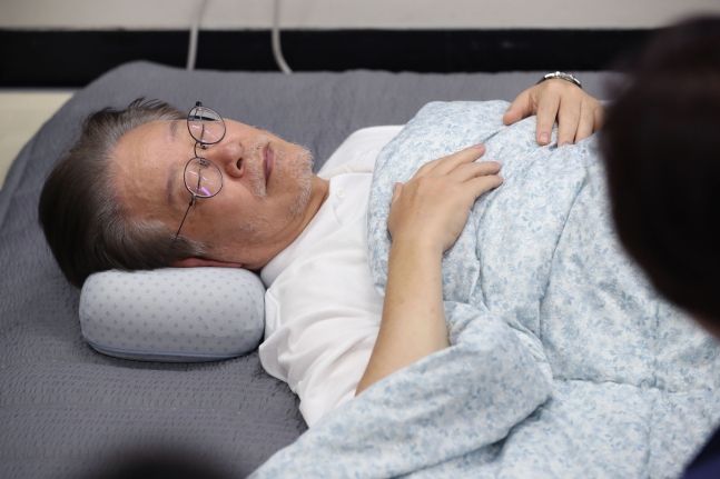 ‘단식 15일차’ 이재명 더불어민주당 대표가 14일 서울 여의도 국회 당대표실에서 누운 채 단식 중단을 요청하는 동료 의원들의 이야기를 듣고 있다. 뉴스1