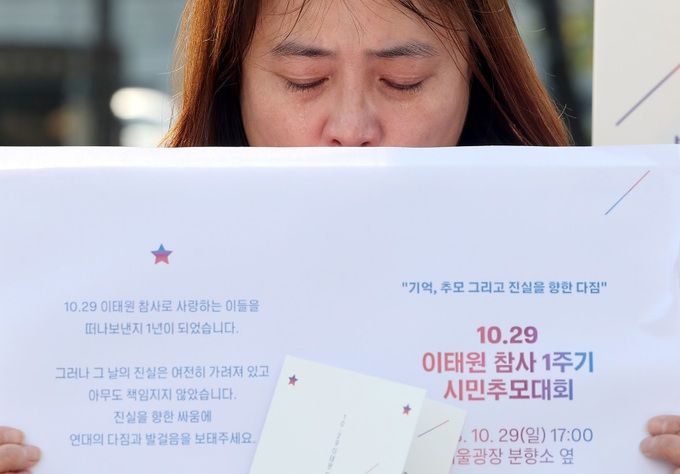 지난 18일 오전 서울 용산 대통령실 앞에서 열린 이태원 참사 1주기 기자회견에서 한 유가족이 1주기 시민추모대회 초대장을 들고 눈물을 흘리고 있다. 연합뉴스