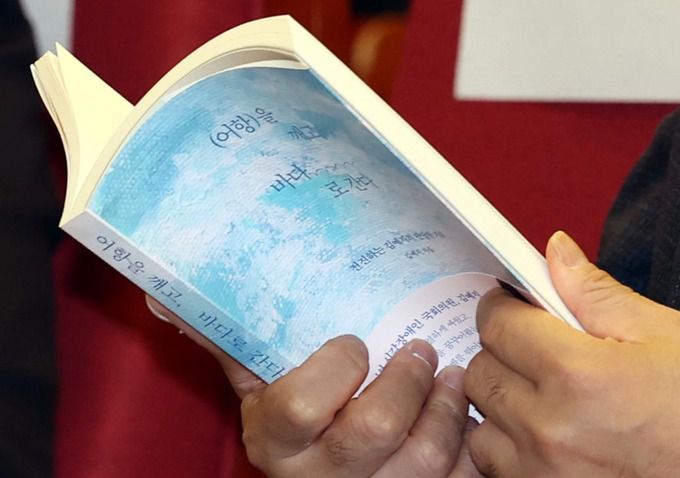 김 의원의 출판기념회를 찾은 한 참석자가 ‘(어항)을 깨고 바다로 간다’ 책을 읽고 있다. 뉴시스