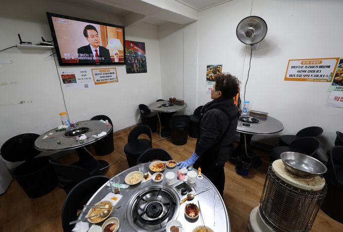 지난 7일 오후 서울 종로구 신진시장 내 한 음식점에서 주인이 윤석열 대통령 KBS 신년대담 방송을 시청하고 있다.   뉴시스