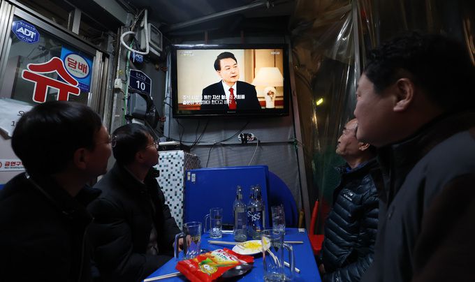 지난 7일 오후 서울 종로구 신진시장 내 한 노포에서 시민들이 윤석열 대통령 KBS 신년대담 방송을 시청하고 있다.    뉴시스