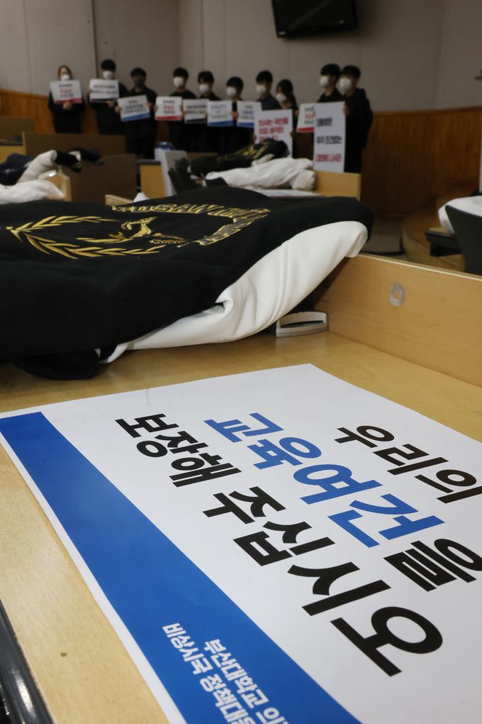 19일 오전 부산대 양산캠퍼스 의과대학 한 강의실에서 교수와 의대생들이 정부의 의대 정원 확대 방침에 반발하는 팻말을 들고 있다. 이날 부산대 의과대학 교수협의회는 기자회견을 열고 오는 25일부터 자발적으로 사직서를 제출한다고 밝혔다. 연합뉴스