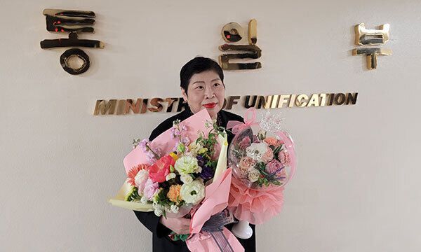 허희옥 통일부 기자실장이 서울정부종합청사 7층 통일부 간판 앞에서 직원들의 인사를 받으며 기념사진을 찍고 있다.