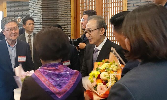 이명박 전 대통령이 17일 포항 송도활어위판장 오찬장소에 도착해 환영 꽃다발을 받고 있다.