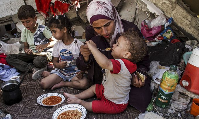 가자지구 북부 자발리야 난민촌에서 한 팔레스타인 여성이 이스라엘의 공격으로 파괴된 건물 잔해에 설치한 그늘막 안에서 아이에게 음식을 먹이고 있다. 신화뉴시스