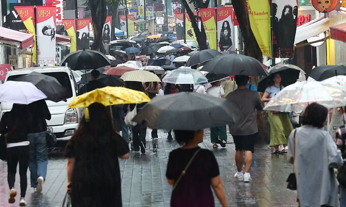 서울 등 중부지방에 비가 내리는 22일 서울 중구 명동에서 외국인 관광객들이 우산을 쓰고 이동하고 있다. 뉴시스