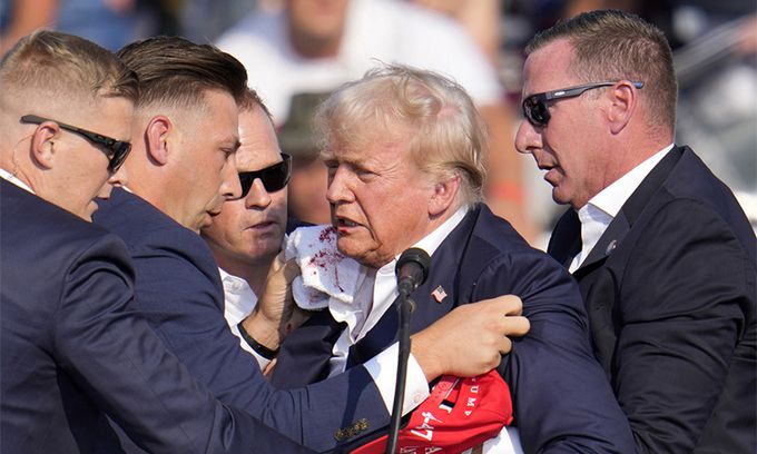 도널드 트럼프 전 미국 대통령이 13일(현지시각) 펜실베이니아주 버틀러에서 유세를 벌이던 중 총성으로 추정되는 소리가 울려퍼지자 연단에서 몸을 숙였다가 귓가에 피를 흘리며 대피하고 있다. AP연합뉴스