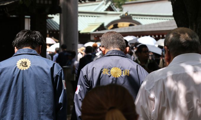 일본 패전일인 15일 태평양전쟁 A급 전범이 합사된 도쿄 지요다구 야스쿠니신사에서 남색 제복을 입은 사람들이 신사를 향해 절하고 있다. 가운데 남성의 옷에 '구국'이라는 글자가 새겨져 있다. 연합뉴스