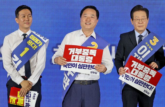 17일 오후 서울 중구 장충체육관에서 열린 더불어민주당 서울시당 제1차 정기전국당원대회 및 당대표·최고위원 후보자 합동연설회에서 당대표 후보로 나선 김지수 후보(왼쪽부터)와 김두관 후보, 이재명 후보가 윤석열 정권을 규탄하는 손피켓을 들고 있다.뉴스1