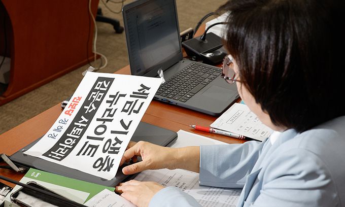 정혜경 진보당 의원이 지난 26일 서울 여의도 국회 환경노동위원회에서 열린 김문수 고용노동부 장관 후보자 인사청문회에서 노트북에 부착한 '세금 기생충 뉴라이트 김문수 사퇴하라' 손팻말을 떼어내고 있다. 뉴스1