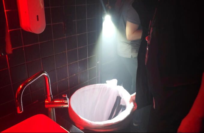 경찰 관계자가 클럽 화장실 쓰레기통을 살펴보고 있다.