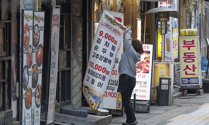 16일 서울 종로의 음식점 밀집 거리에서 한 가게 관계자가 영업을 시작하기 위해 입간판을 설치하고 있다. 연합뉴스