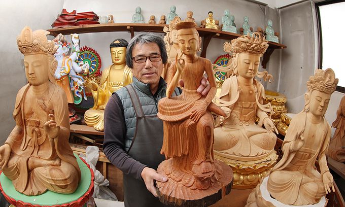 완성된 반가사유상을 들어 보여 미소를 짓고 있는 하명석 목불조각장.