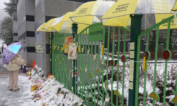 12일 대전 초등학생 피살사건이 발생한 대전 서구의 한 초등학교 정문에 추모객들이 놓고 간 국화과 편지 위에 우산이 설치돼 있다. 뉴스1