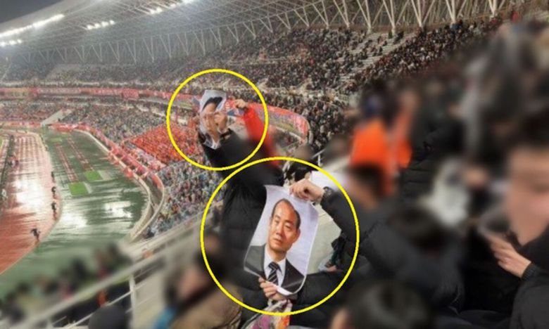 지난 11일 광주FC와 중국 산둥 타이산의 ‘2024-2025 아시아축구연맹(AFC) 챔피언스리그 엘리트(ACLE) 리그 7차전’이 열린 중국 산둥성 지난 올림픽 스포츠센터 관중석에서 광주 팬들을 자극하려는 듯 전두환 전 대통령(아래쪽 노란 동그라미) 사진과 북한 김정은 국무위원장으로 보이는 사진(위쪽〃)을 든 관중이 눈에 띈다. 독자 제공