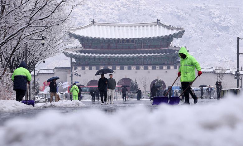 난데없는 3월 대설주의보가 발효된 18일 오전 서울 광화문광장에서 관계자들이 눈을 치우고 있다. 뉴스1