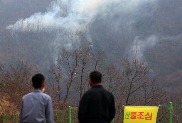 27일 경북 의성군 옥산면 금봉저수지에서 주민이 번져나가는 산불을 바라보고 있다. 연합뉴스