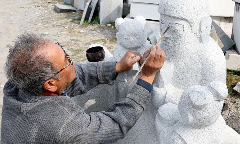고석산 석장이 산신상 얼굴에 붓으로 상호를 그리고 있다.