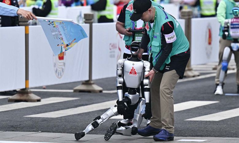일부는 제대로 달리지 못해 한 로봇이 중심을 잃고 쓰러지자 관계자들이 일으켜 세우고 있다. 베이징=AFP연합뉴스