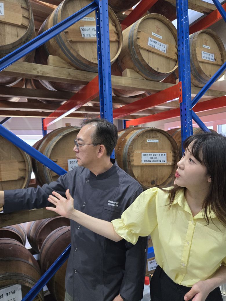 방송인 김민아와 오규섭 온 증류소 대표가 2025년 가을에 출시 예정인 오크통 숙성 소주의 저장고를 구경하고 있다. 온 증류소 제공